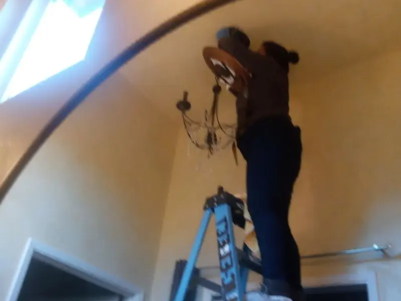 Electrician installing a chandelier in a Medina residence